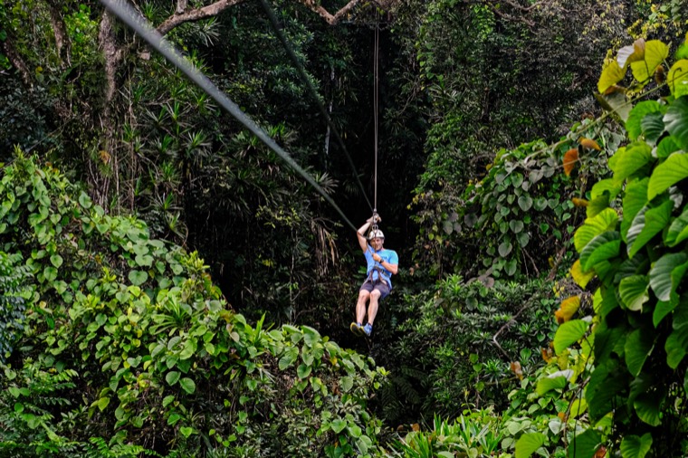 A child ziplining through dense rainforest, Fiji
